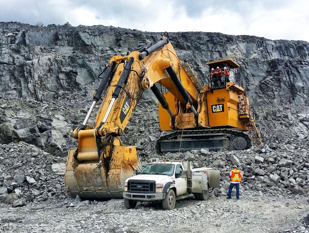 A Large CAT Excavator with a Ford Truck and a Person for scale