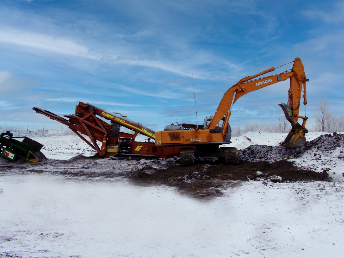 An Orange Hitachi Excavator operates in the snow to dig up soil